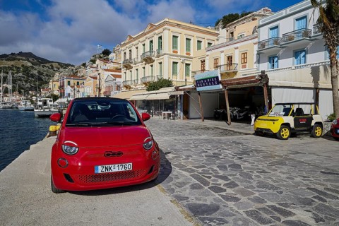 Red car on a promenade in a coastal town with Mediterranean architecture, Symi Town, Symi,
