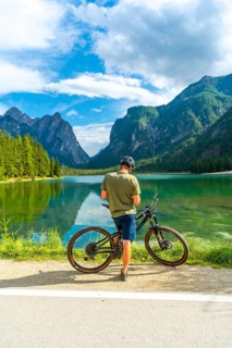 Mountain biker enjoying the breathtaking view of lake dobbiaco and the surrounding dolomites peaks