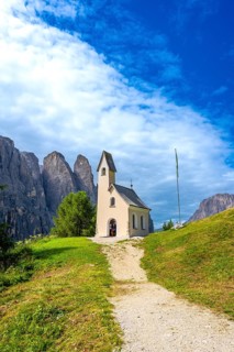 Small church at passo gardena with the dolomites in the background during a sunny summer day