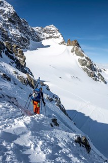 Mountaineer with skis at the fork Porta d'Es-cha, view of mountain peak Piz Kesch and glacier