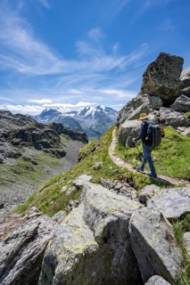 Mountaineer on hiking trail in mountain landscape, descent at Col du Louvie, view of the summit of
