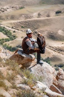 Traditional Kyrgyz eagle hunter hunting in the mountains in a dry landscape, near Kysyl-Suu, Issyk