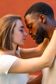 Vertical photo of a young multi-ethnic couple sharing a romantic moment embracing face to face