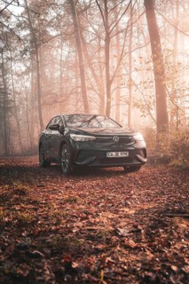 A Volkswagen in a peaceful atmosphere in a foggy, autumnal forest with incidence of light, electric