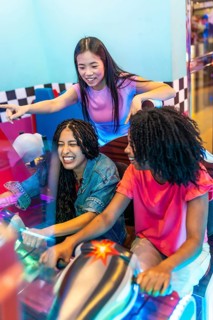 Group of female friends enjoying a lively gaming session, laughing and competing in a racing game