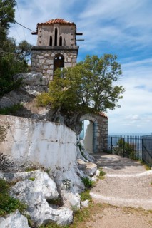 An old stone tower stands by the wayside under a clear blue sky, rock church of Smerna, Church of