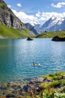 Woman bathing in mountain lake Lac de Louvie, behind summit of Grand Combin, Val de Bagnes, Valais,