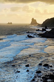 Beach of Playa de Benijo at high tide with the rock Roques de Anaga in the light of the rising sun,