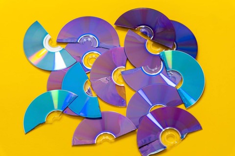 Top view of cut CDs and DVDs against a yellow background
