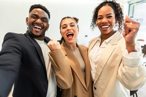 Enthusiastic businesspeople cheering and expressing joy after achieving a goal, showing teamwork