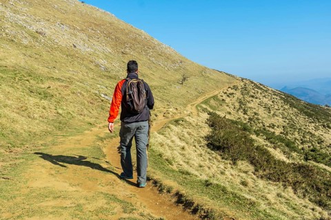 A man descending from the summit of Mount Ernio or Hernio in Gipuzkoa at sunset, Basque Country