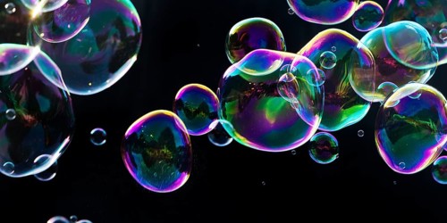Iridescent soap bubbles in the colours of the rainbow against a black background, Recklinghausen,