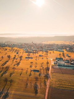 Extensive fields and trees with village in the background, in a misty autumn landscape, Neubulach,