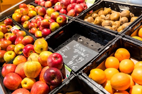 Fruit counter in a supermarket or organic food shop, here with different types of apples, kiwis,