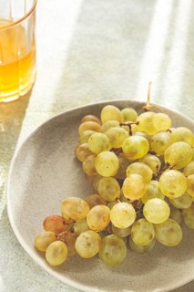 A branch of white grapes, on a gray plate, with a glass of white wine, top view, natural light,