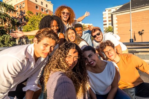 Frontal view of a multi-ethic cheerful friends taking selfie together in the city