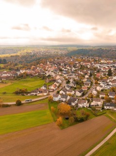 Aerial view of a village surrounded by autumnal fields under a cloudy sky, Tiefenbronn, Germany