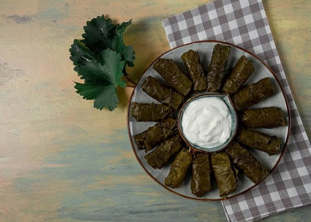 Dolma, cabbage rolls in grape leaves, Traditional Armenian dish, with white sauce, top view,