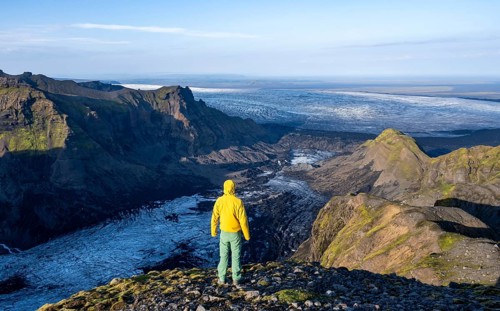 Young man, tourist in front of impressive landscape with glacier in the evening light, glacier