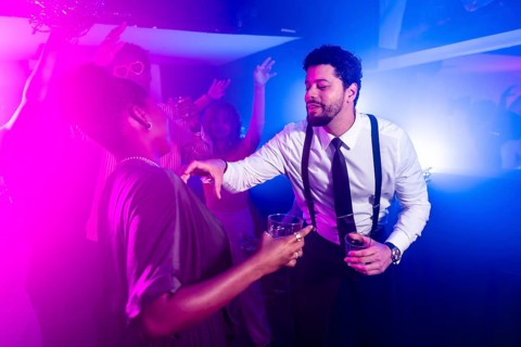 Businessman flirting with beautiful woman while holding alcoholic beverages and dancing at