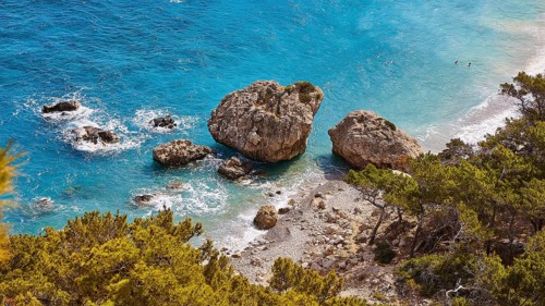Large rocks in the turquoise sea on a coast overgrown with pine trees, Kato Lakkos Beach, still