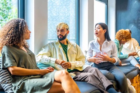 Side view of three coworkers chilling and talking in a comfortable sofa
