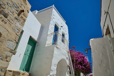 Traditional building with white walls and flowers under a bright blue sky, Chora, Astypalea,