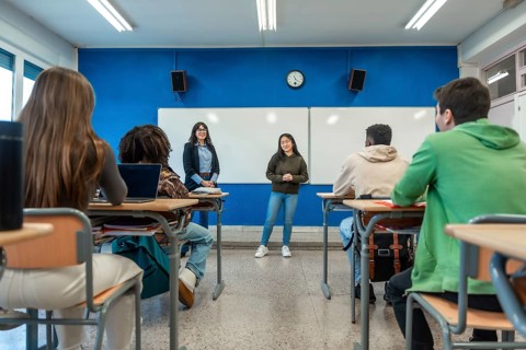 Confident young woman giving a presentation to her classmates and teacher in a modern university