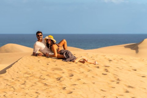 Couple relaxing on the warm sand of maspalomas dunes, enjoying the stunning ocean view and creating