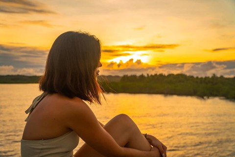 Young woman enjoying a peaceful golden sunset over the tropical landscape of siargao island,