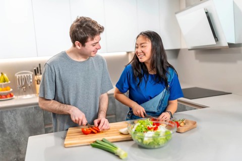 Asian woman and caucasian man enjoying quality time in a modern kitchen, chopping vegetables and
