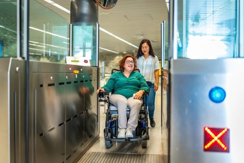 Smiling caucasian adult disabled woman in a wheelchair and chinese caregiver exiting the metro