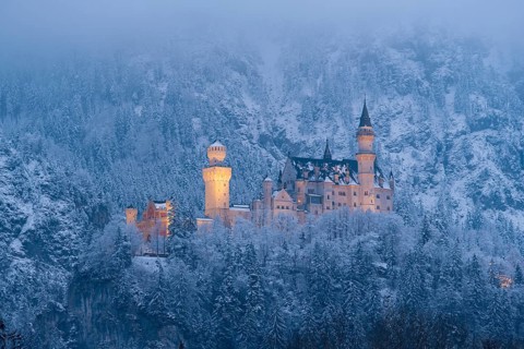 A fabulously illuminated castle in the misty winter landscape at night, Neuschwanstein, Schwangau,