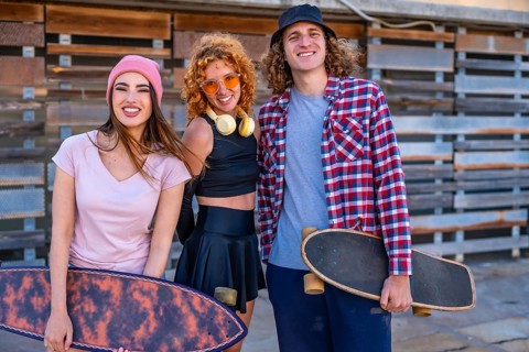 Group of cheerful friends enjoying time at skateboarding park. Female and male skaters standing