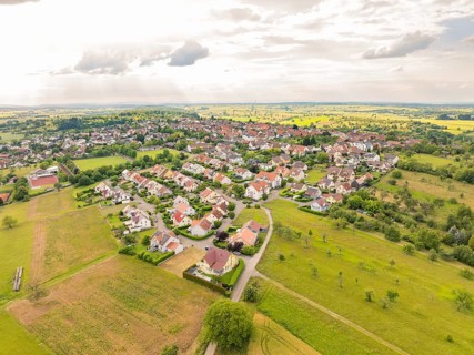 Overview of a residential area with many houses and streets, surrounded by wide fields under a