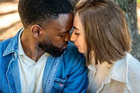 Close up of a beautiful Mixed-race young couple enjoying each other rubbing roses and embracing in