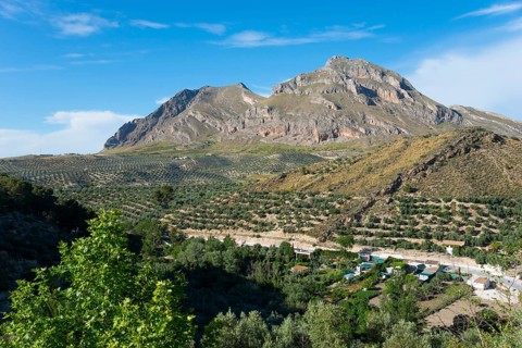 Majestic mountains and green landscape with scattered houses and trees under a clear blue sky, Alto