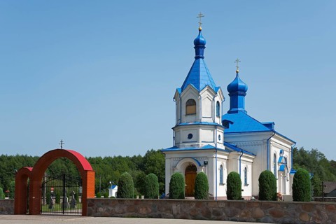 Orthodox church with blue roof and magnificent archway, surrounded by green landscape, Orthodox