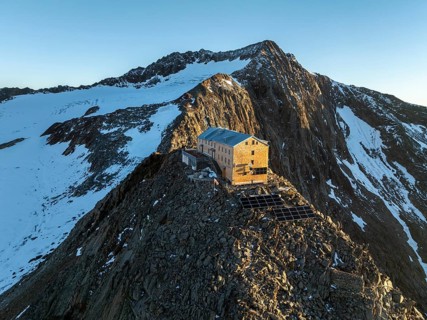 Atmospheric sunrise in a picturesque mountain landscape, alpenglow, aerial view, mountain hut