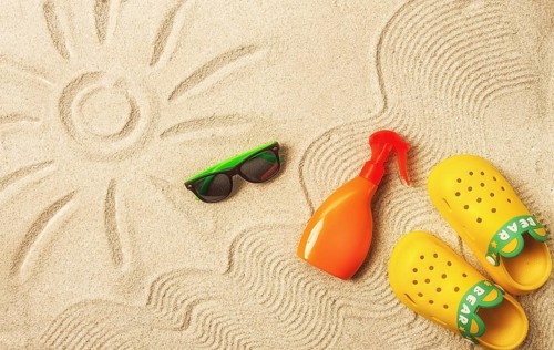 Drawing on the sand, sun and waves, sunglasses, with an orange bottle, yellow rubber slippers, sun