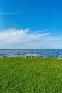 Isolated, white, empty bench in a meadow on the shore of the Szczecin Lagoon in the village of