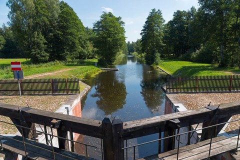 A wooden lock opens onto a quiet river surrounded by trees, Tartak Lock, Augustow Canal,