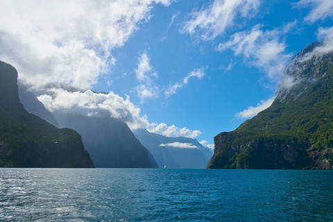 Majestic fjord with dominant mountains and few clouds under a blue sky, summer, Milford Sound, Te