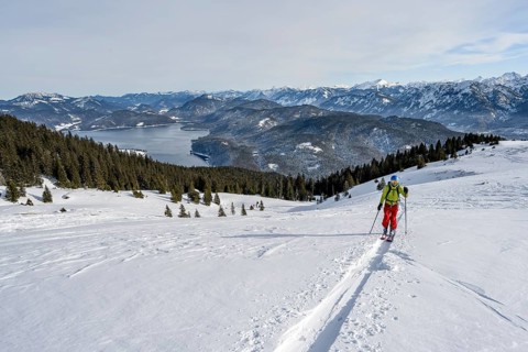 Ski tourers ascending Simetsberg, view of Walchensee and mountain panorama, Estergebirge, Bavarian