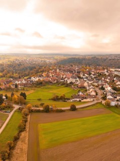 View of a village with autumnal fields and clouds, Tiefenbronn, Germany
