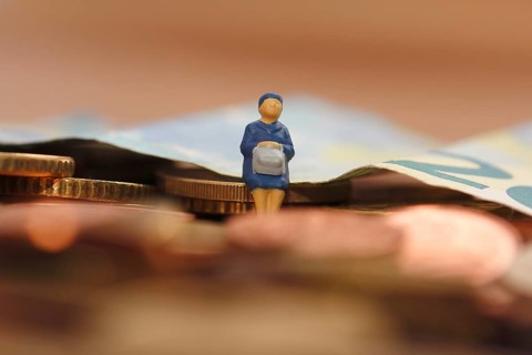 Miniature woman sitting on euro coin, twenty euro note in the background, North Rhine-Westphalia,