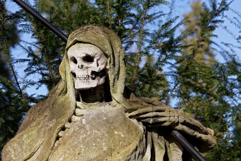 Grim Reaper, allegory of death with hourglass and scythe, sculpture at the Melaten Cemetery,