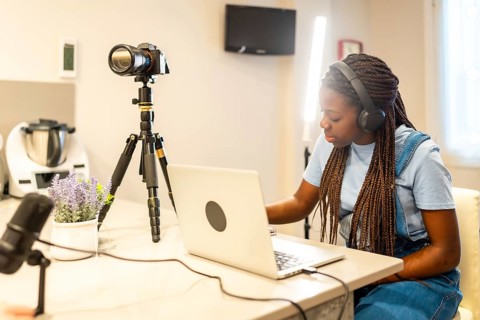Young girl recording a vlog at home, using a camera, headphones, and microphone, immersed in her