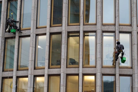 Window cleaners hanging on the facade of a commercial building, Potsdamer Platz, Berlin, Germany