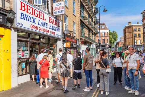 Customers queuing outside a bagel shop, Brick Lane Market, East End, London, England, United